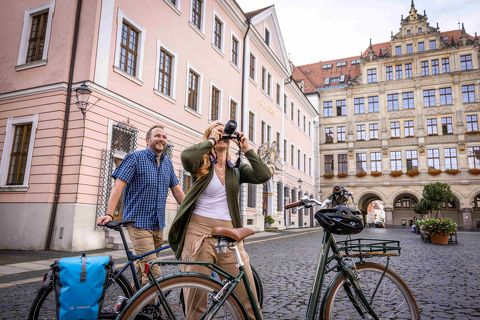 Ein Paar steht mit Fahrrädern auf dem  Untermarkt in Görlitz. Die Frau fotografiert.